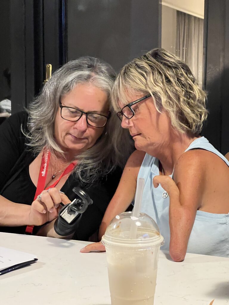 Leslie and Laura looking at a Laura's prosthetic hook.